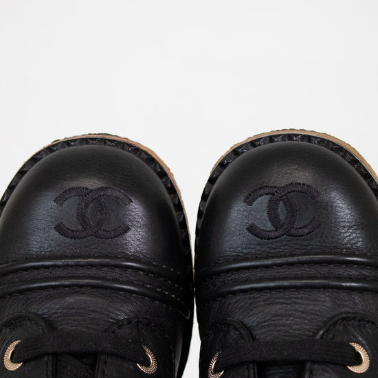 Pair of black leather shoes with Chanel logo on a white background