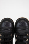 Pair of black leather shoes with Chanel logo on a white background