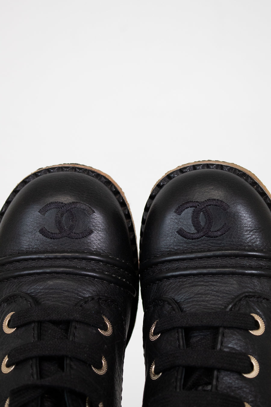Pair of black leather shoes with Chanel logo on a white background