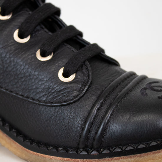 Close-up of a black leather boot with laces on a light background