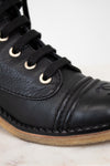 Close-up of a black leather boot with laces on a light background