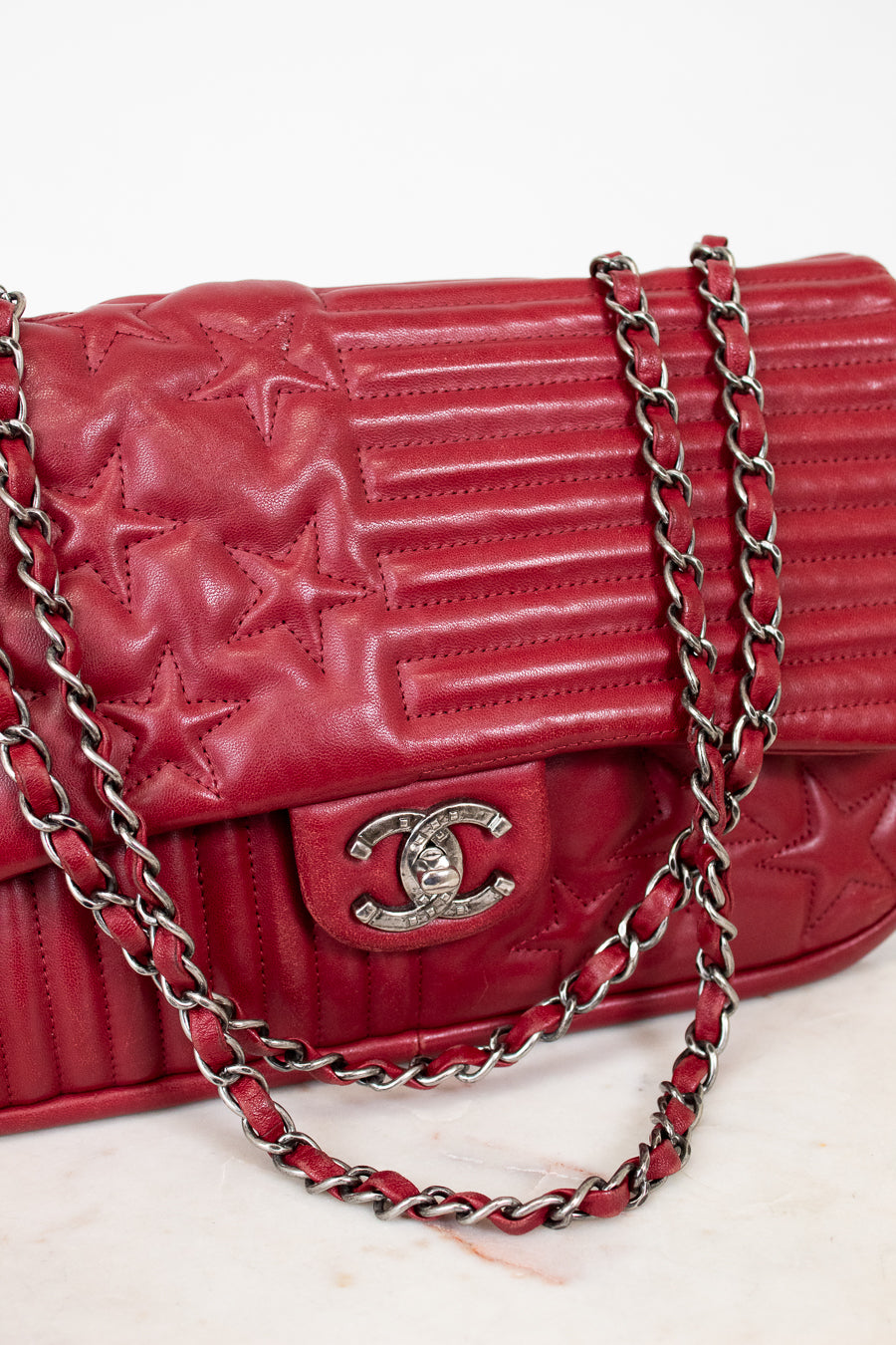 Red quilted handbag with a chain strap on a light background