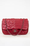 Red quilted handbag with a chain strap on a white background
