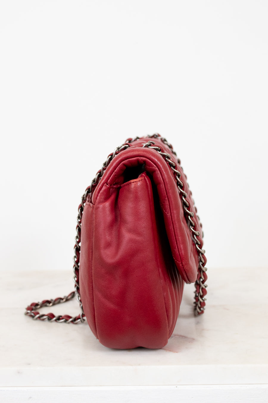 Side view of red leather handbag on white background