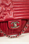 Red quilted handbag with Chanel logo and chain detail on a light background