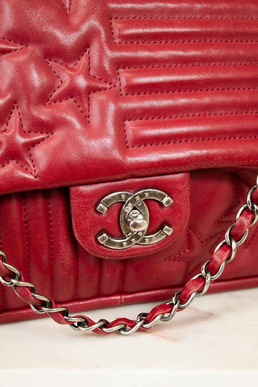 Red quilted handbag with Chanel logo and chain detail on a light background