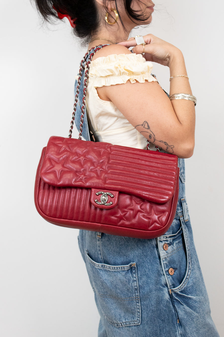 Person holding a red quilted handbag with a visible brand logo against a plain background