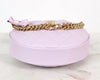 Pink round bottom of handbag with gold chain and bow on a white background