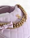 Chanel handbag with gold chain and bow detail on a white background