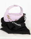 Purple handbag with gold chain and black Chanel cloth on a white background
