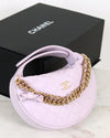 Lilac bag with gold chain and Chanel logo in front of a black Chanel box.
