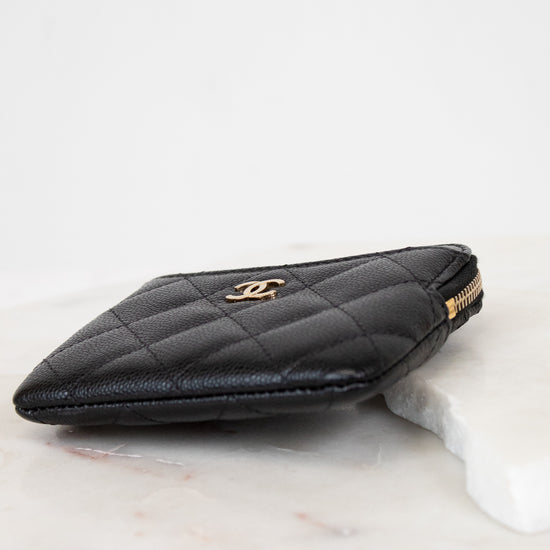 Black quilted wallet with gold logo on a white background