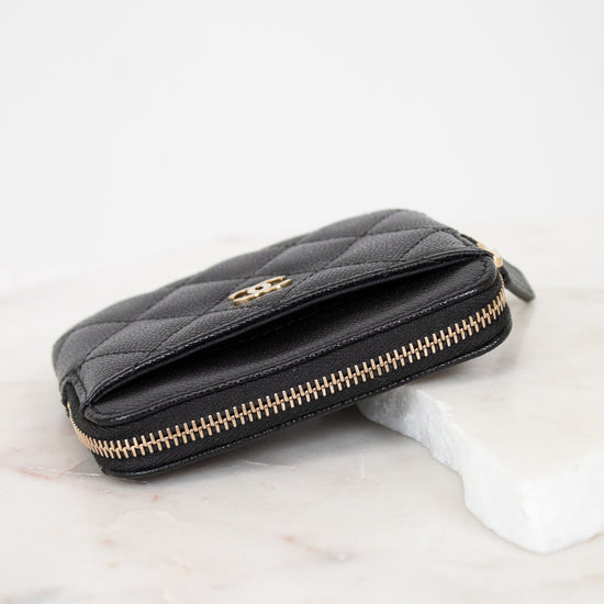 Black quilted wallet with gold logo on a white background