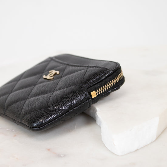 Black quilted wallet with gold logo on a white background