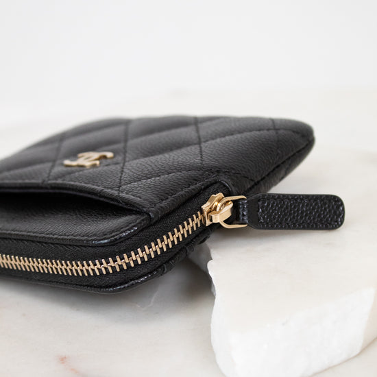Black quilted wallet with gold logo on a white background