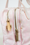 Close-up of a pink Chanel handbag with gold zippers on a light background