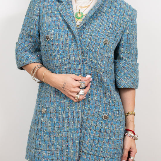 Person wearing a blue tweed jacket on a plain background
