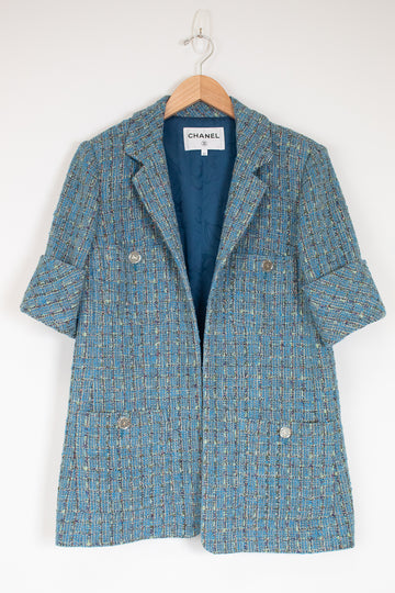 Blue tweed coat on a hanger with Chanel label