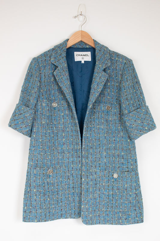 Blue tweed coat on a hanger with Chanel label