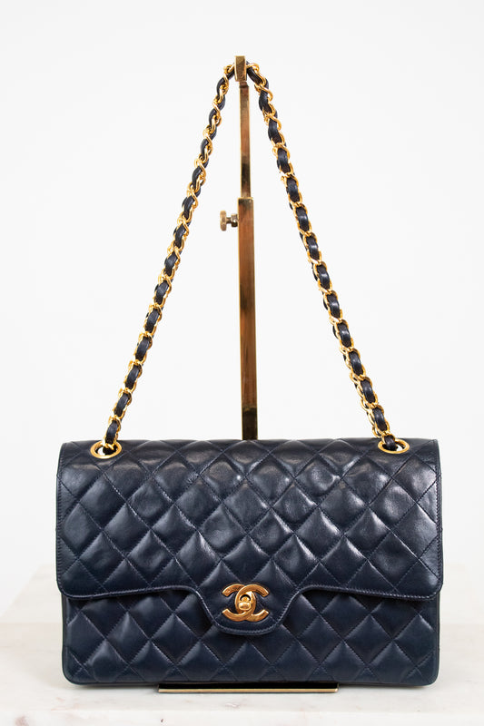 Navy blue quilted handbag with gold chain strap on a white background