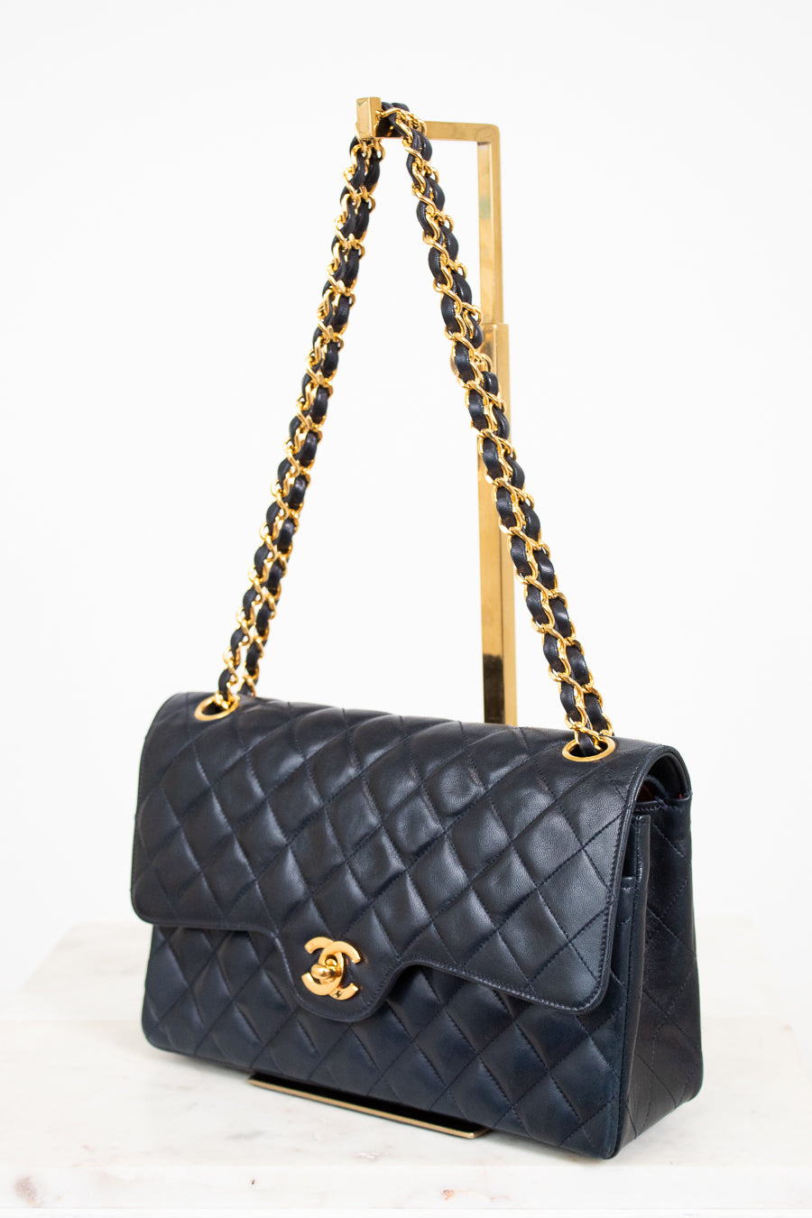 Navy quilted handbag with gold chain strap on a white background