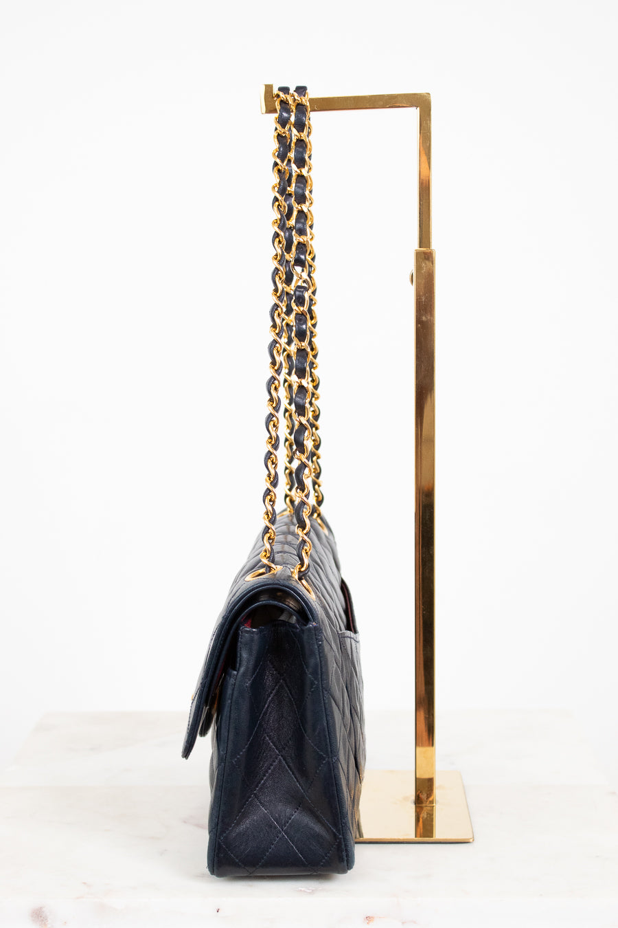 Navy handbag with gold chain on a white background