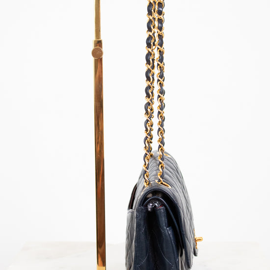 Navy handbag with gold chain strap on a white background