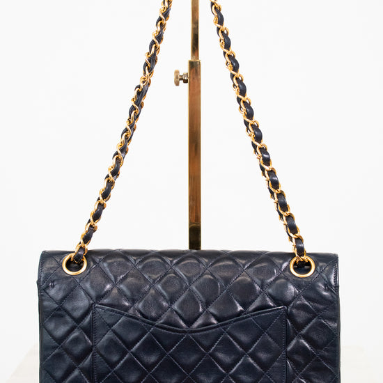 Navy quilted handbag with gold chain strap on a white background