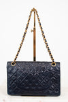 Navy quilted handbag with gold chain strap on a white background