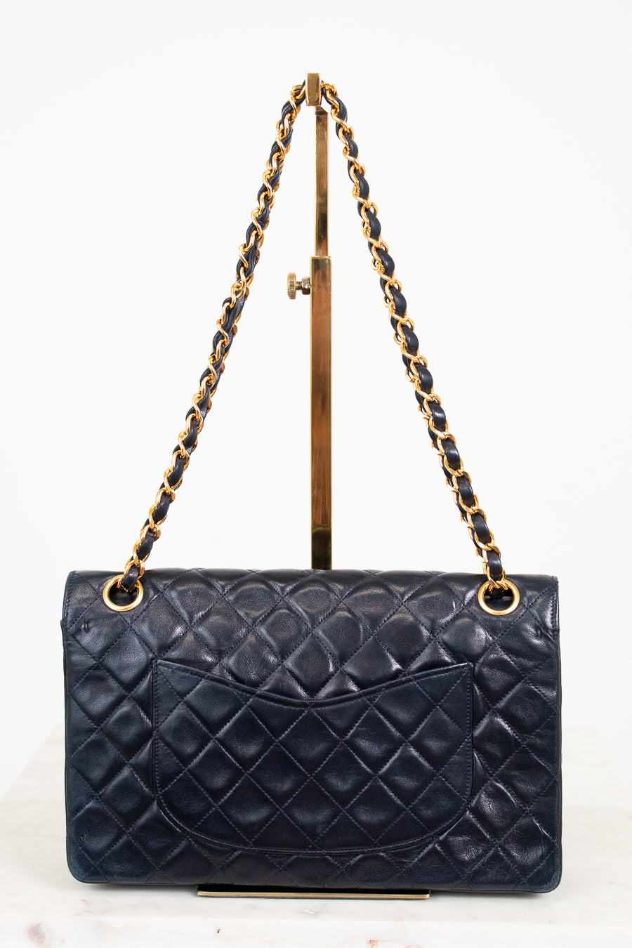 Navy quilted handbag with gold chain strap on a white background