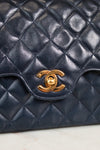 Navy quilted leather handbag with gold Chanel logo on a light background