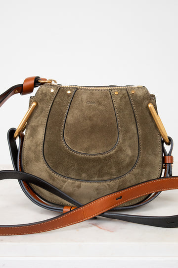 Olive suede handbag with a brown strap on a white background