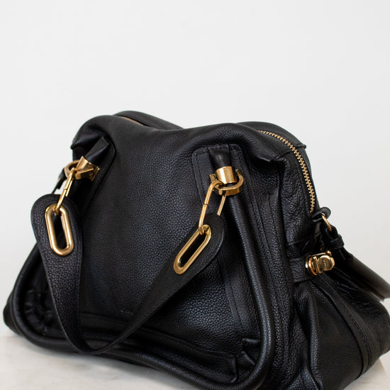 Black handbag with gold hardware on a white background