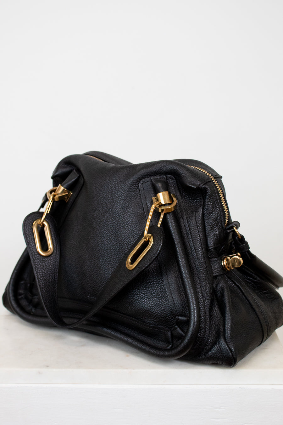 Black handbag with gold hardware on a white background