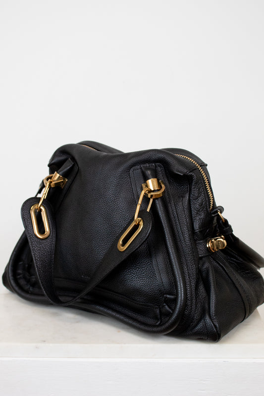 Black handbag with gold hardware on a white background