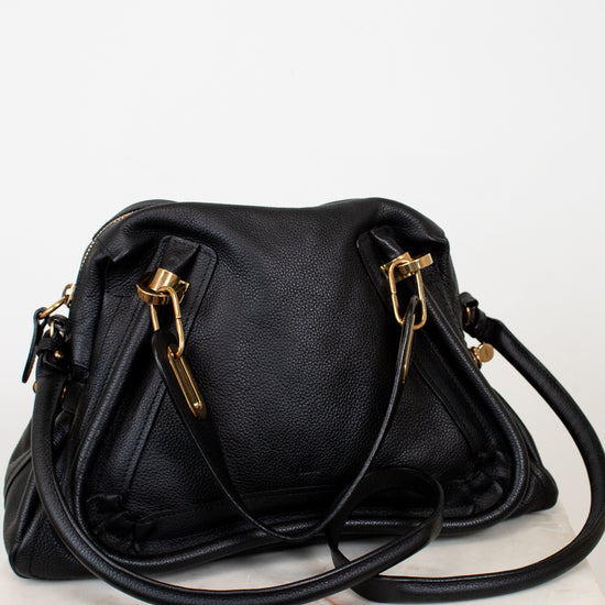 Black handbag with gold hardware on a white background