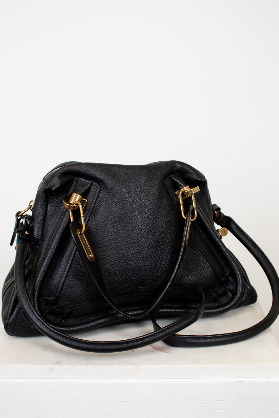 Black handbag with gold hardware on a white background