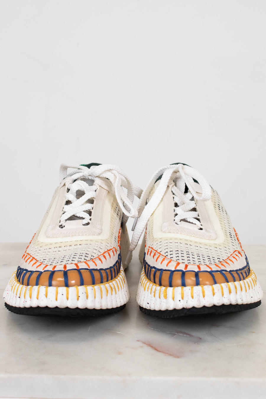 Pair of white sneakers with colorful soles on a light gray background