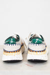 Pair of white sneakers with green and blue accents on a light background