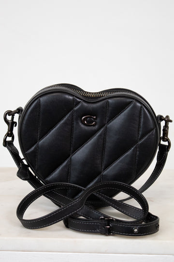 Black quilted heart-shaped handbag with a brand logo on a white background