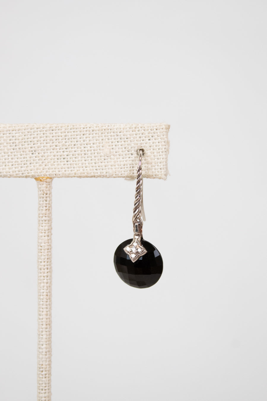 Black faceted bead earring with silver hook on a white background
