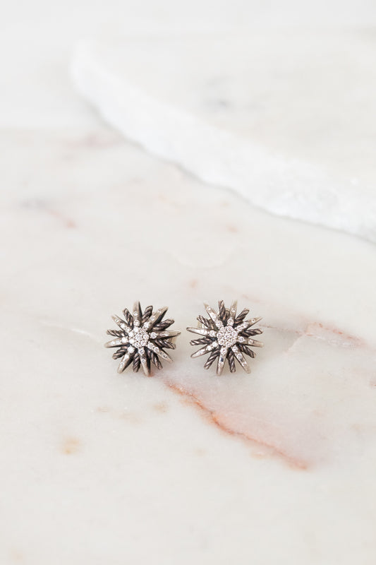 Silver starburst-shaped earrings on a marble surface
