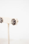 Silver earring with starburst design on a white background
