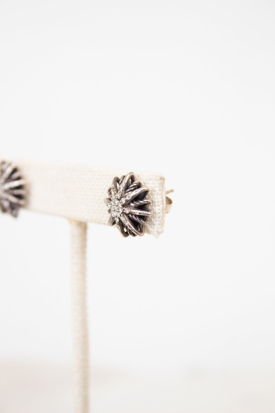 Silver earring with starburst design on a white background