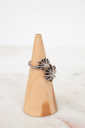 Silver starburst style ring on wooden cone with white background
