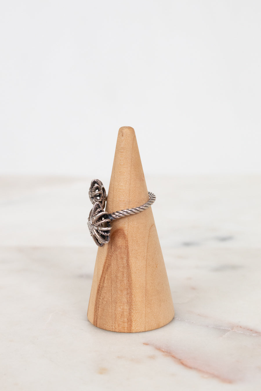 Silver ring on a wooden cone against a marble background