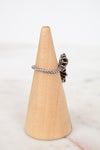 Silver ring with a unique design on a wooden cone against a white background