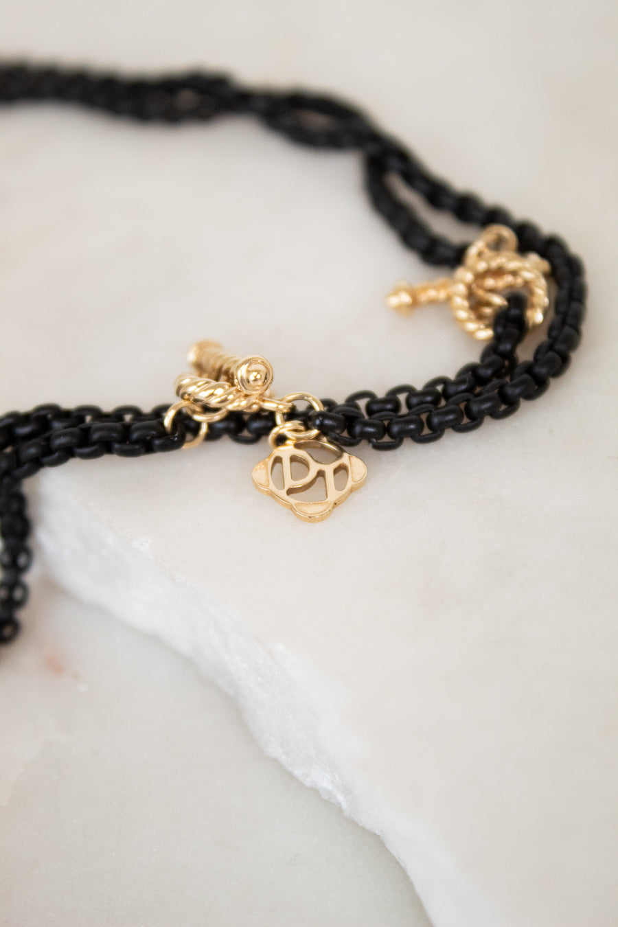 Black chain with gold charms on a white surface