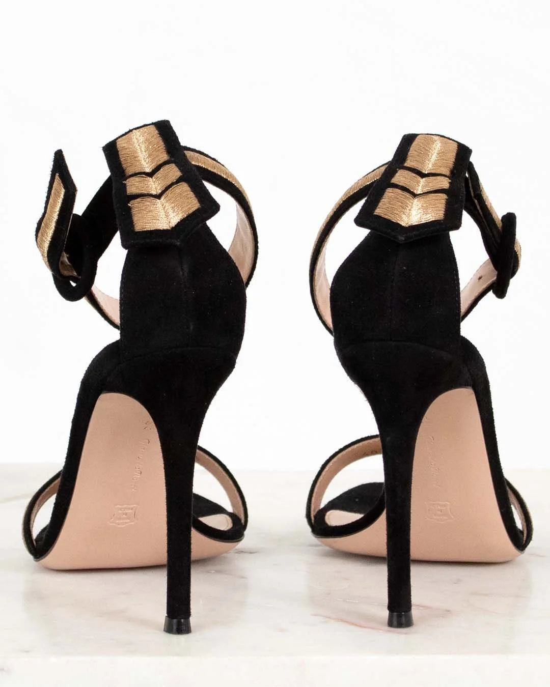Black high-heeled shoes with gold accents on a white background