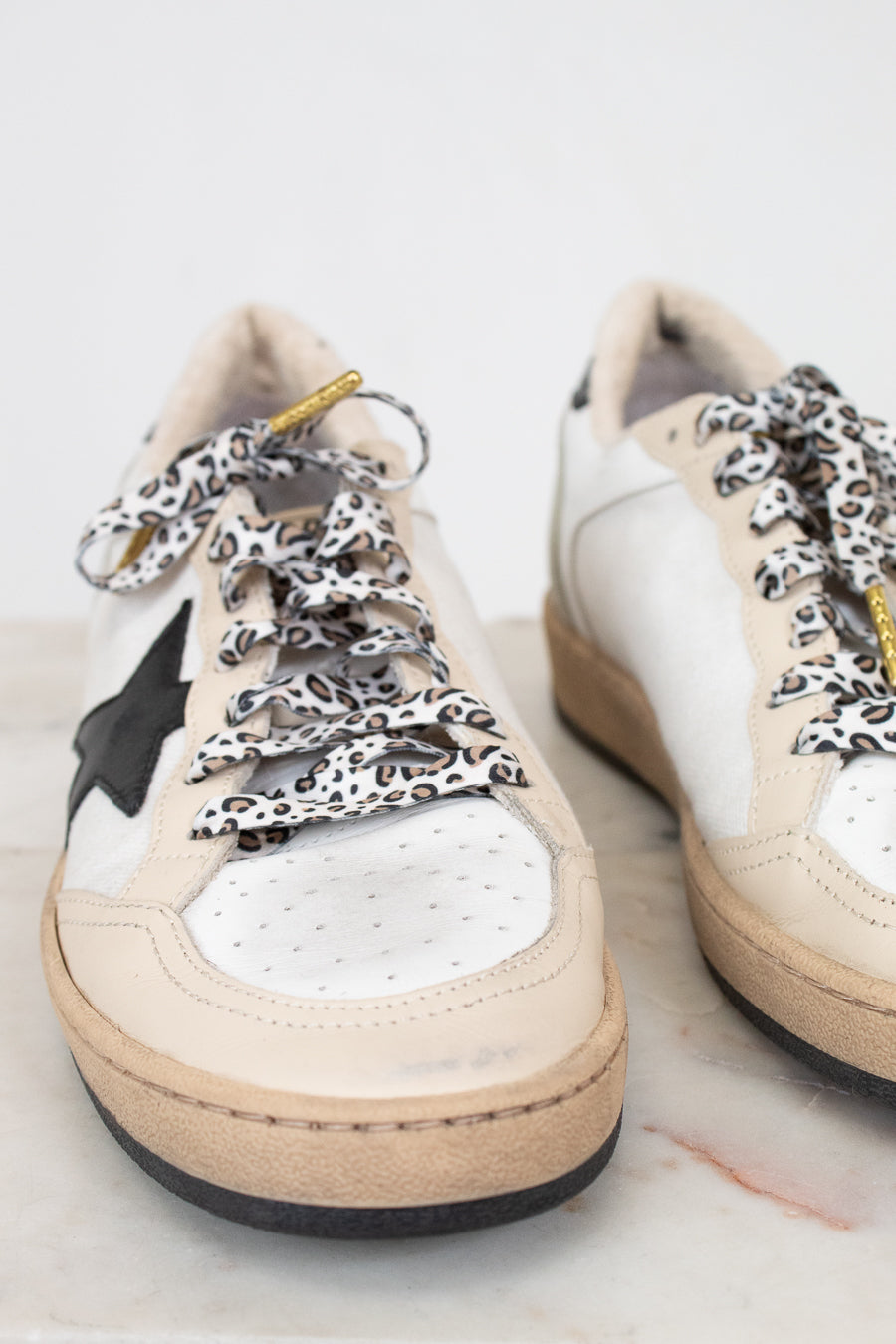 White sneakers with leopard print laces on a light background